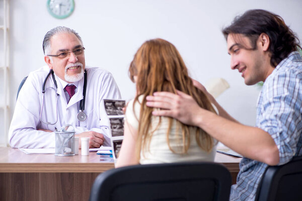 Молодая пара, посещающая пожилого врача
