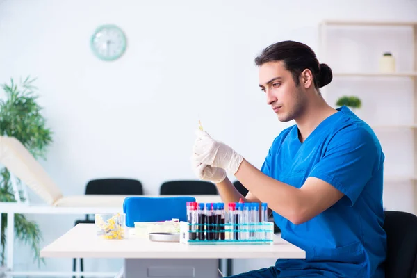 Asistente de laboratorio joven analizando muestras de sangre en el hospital — Foto de Stock