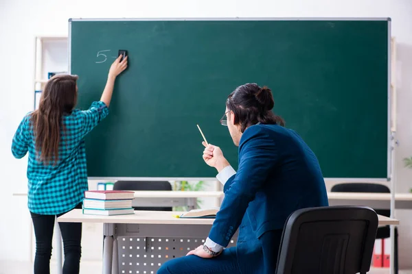 Young handsome teacher and female student in the classroom — Stock Photo, Image