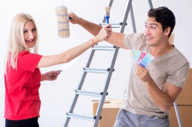 Ev tadilatı sırasında genç bir aile boya işi yapıyor.