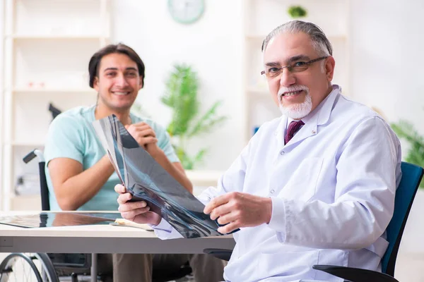 Paciente masculino em cadeira de rodas visitando médico velho — Fotografia de Stock