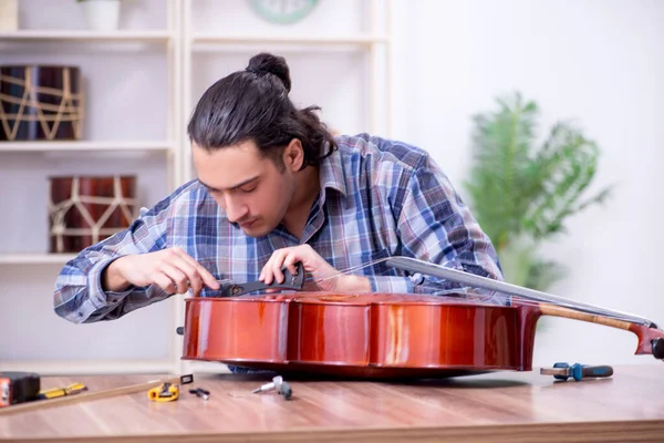 Jeune beau réparateur réparer violoncelle — Photo