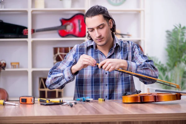 Jonge knappe reparateur die viool repareert — Stockfoto