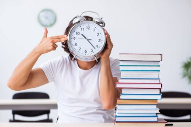 Sınıfta oturan genç erkek öğrenci.