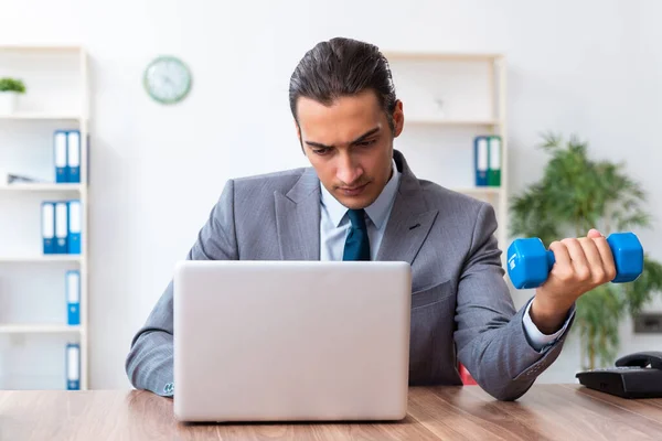 Ung stilig anställd gör sport övningar på arbetsplatsen — Stockfoto