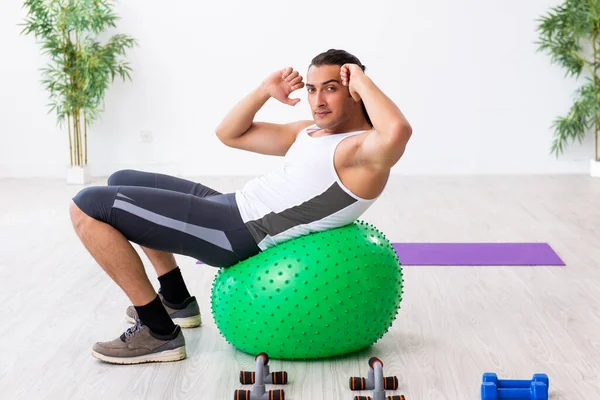 Young handsome man doing sport exercises indoors — Stock Photo, Image