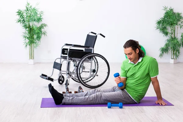 Młody mężczyzna na wózku inwalidzkim ćwiczy w pomieszczeniu — Zdjęcie stockowe