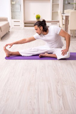 Genç adam evde fiziksel egzersiz yapıyor.