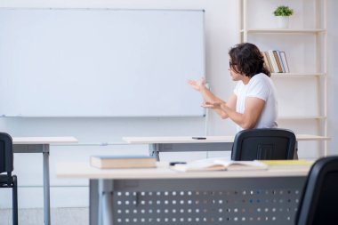 Beyaz tahtanın önünde genç bir erkek öğrenci.