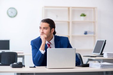 Genç erkek işadamı ofiste oturuyor.