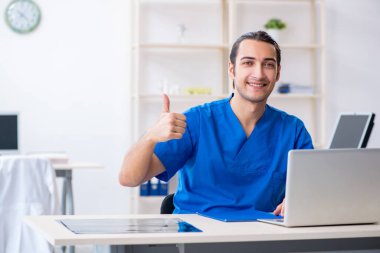 Klinikte çalışan genç erkek doktor.