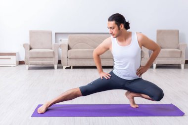 Genç adam evde antrenman ve egzersiz yapıyor.