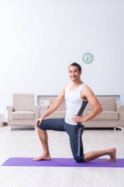 Genç adam evde antrenman ve egzersiz yapıyor.