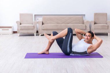 Genç adam evde antrenman ve egzersiz yapıyor.