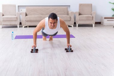 Genç adam evde antrenman ve egzersiz yapıyor.