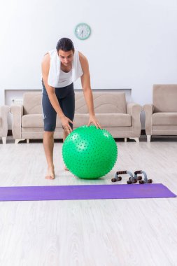 Genç adam evde antrenman ve egzersiz yapıyor.