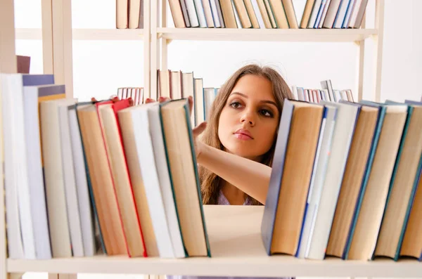 Ung kvinnlig student förbereder sig för tentamen på biblioteket — Stockfoto