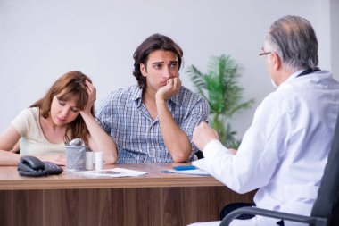 Genç çift yaşlı erkek doktoru ziyaret ediyor.