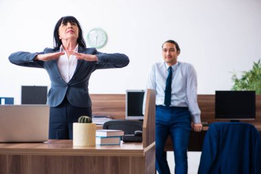 Ofiste spor egzersizleri yapan iki çalışan.