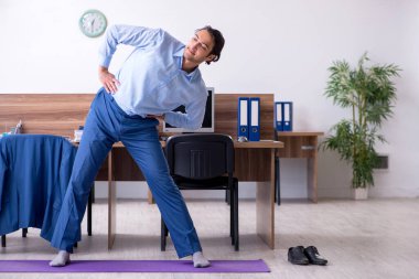 Genç yakışıklı işadamı iş yerinde egzersiz yapıyor.