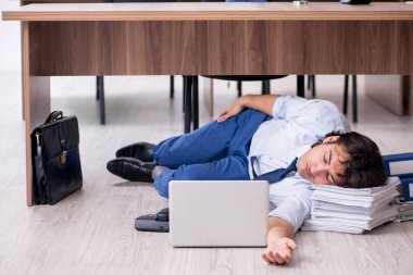 Genç bir erkek işçi ve ofiste çok fazla iş var.