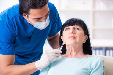 Yaşlı kadın estetik ameliyat için erkek doktoru ziyaret ediyor.