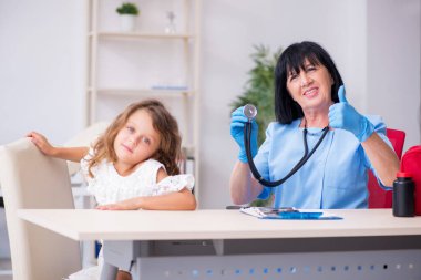 Küçük kız yaşlı kadın doktoru ziyaret ediyor.