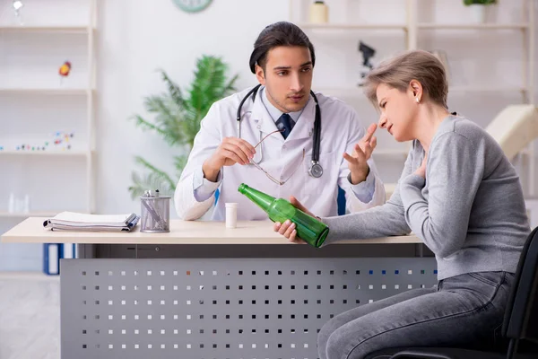 Mulher alcoólica visitando jovem médico masculino — Fotografia de Stock