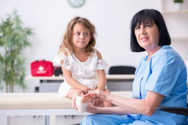 Küçük kız yaşlı kadın doktoru ziyaret ediyor.