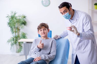 Genç çocuk hastanede doktoru ziyaret ediyor.