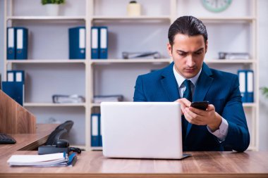 Genç yakışıklı işadamı ofiste çalışıyor.