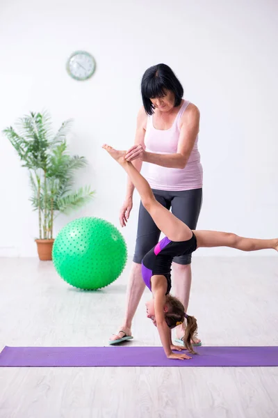 Menina e mãe se exercitando em casa — Fotografia de Stock