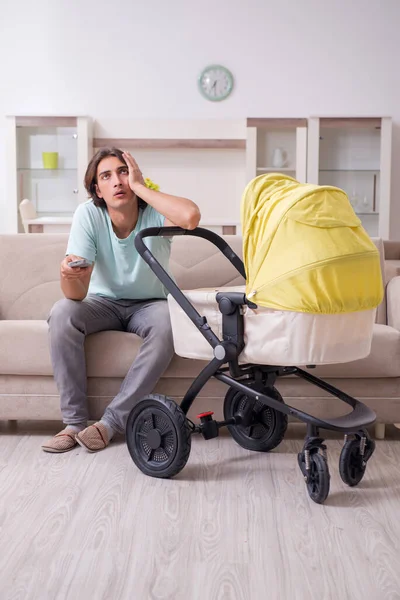 Jeune homme s'occupant du bébé en landau — Photo