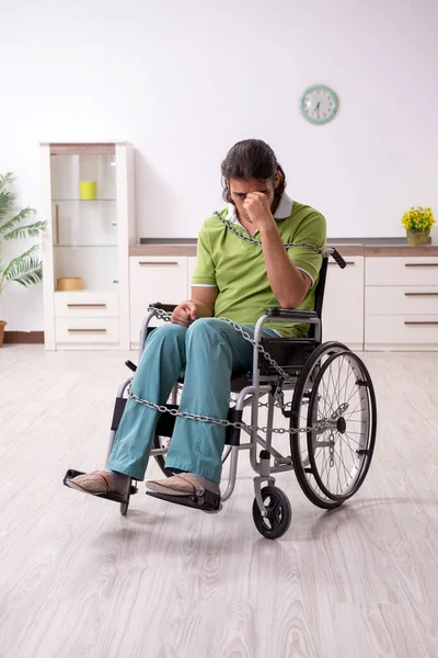 Joven hombre inválido en silla de ruedas sufriendo en casa — Foto de Stock