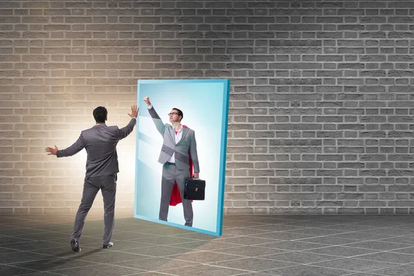 Businessman seeing himself in mirror as superhero