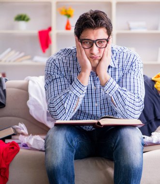 Genç adam dağınık bir odada çalışıyor.