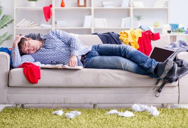 Genç adam dağınık bir odada çalışıyor.