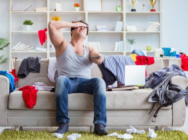 Genç adam dağınık bir odada çalışıyor.