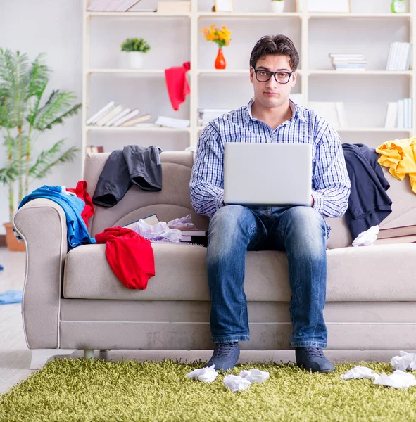 Jeune homme travaillant dans une chambre désordonnée — Photo