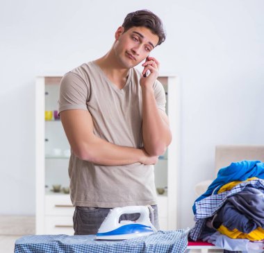 Genç adam evde çamaşır ütülüyor.