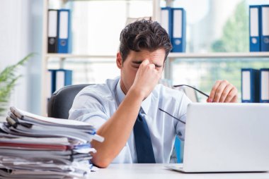 Yorgun iş adamı ofiste oturuyor.