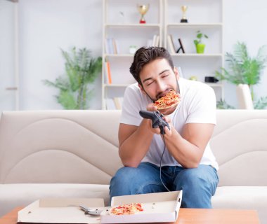 Pizza yiyen adam evde yemek yiyor, dinleniyor.