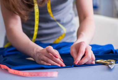 Kadın terzi dikiş dikmek için dikiş dikiyor.