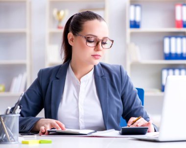 Hesap makinesiyle ofiste çalışan bir muhasebeci.