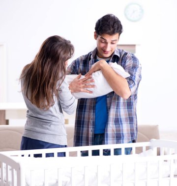 Yatağın yanında yeni doğmuş bebekleri olan genç ebeveynler.