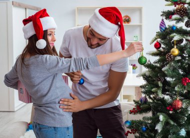 Genç aile Noel 'i kutlayan bir bebek bekliyor.