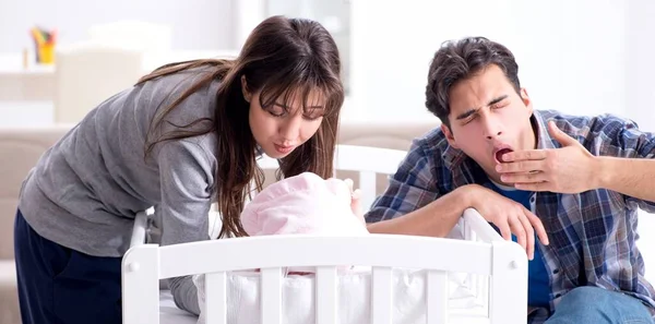 Los padres jóvenes con su bebé recién nacido cerca de la cuna — Foto de Stock