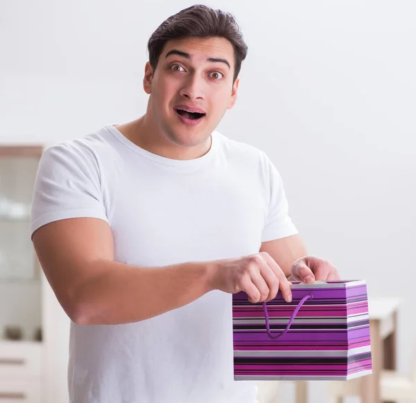 Le jeune homme avec sac cadeau à la maison préparant la surprise pour la femme — Photo