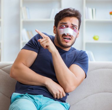 Genç adam estetik cerrahi burnundan sonra evde iyileşiyor.