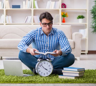 Genç yakışıklı adam evde yerde oturuyor.